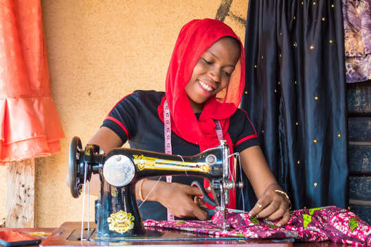 young african woman who is a tailor working on a dress smiling
