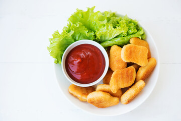 Chicken nuggets with sauce and herbs in a plate, top view