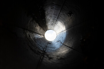 Abstract black tunnel made with round pipe. Concept of exit or endless. A light in the end of a...