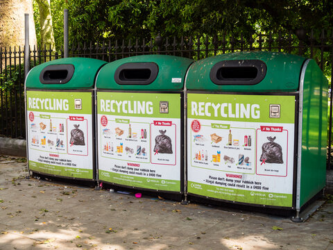 London, UK, June 5th 2021: Three large green recycling bins from Camden Council. For disposing of paper, cardboard, plastics, bottles, metals and glass. Part of London recycles campaign.