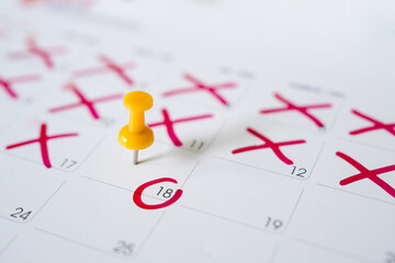 Calendar with yellow pins on May 18. Reminder or deadline concept. Closeup of red pins and red circles.