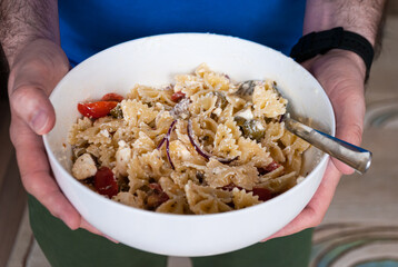 Close-up hands men hold a bowl with pasta salad