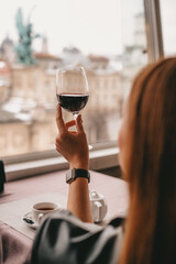 wine tasting in a restaurant. girl in a restaurant with a panoramic view of the city holds a glass of wine. woman drinking wine at a party