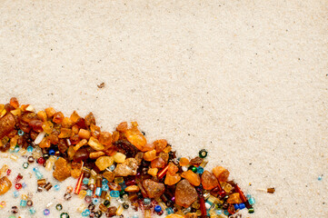 Stars falling. amber and beads on white sand background.