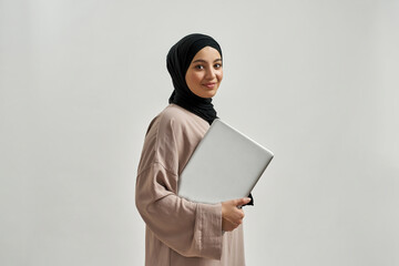 Happy young arabian girl holding laptop while posing