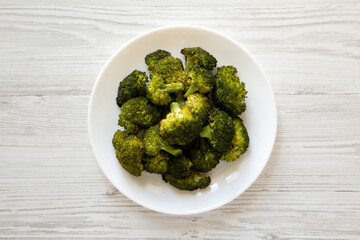 Homemade Roasted Broccoli with Salt and Pepper on a plate on a white wooden surface, top view. Flat lay, overhead, from above.