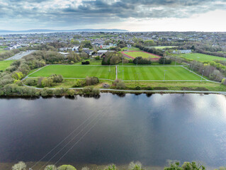 Fototapeta premium Aerial view on a park with Irish sport training ground for camogie, hurling, rugby, gaelic football, soccer. Tall goal posts. Galway city, Ireland. Warm sunny day