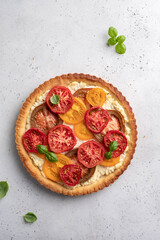 Quiche with colorful tomatoes, riccota, cream cheese and small basil leaves