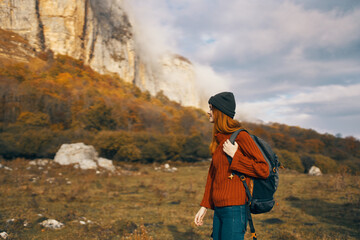 woman in a sweater with a backpack walks in the autumn in the mountains outdoors recreation model vacation