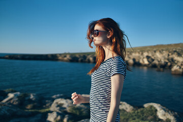 Fototapeta na wymiar happy traveler in glasses and t-shirts near the sea in the mountains blue sky summer side view