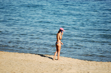 A young woman in a swimsuit is phoning at the beach of Villajoyosa-Spain.