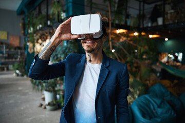 Cheerful young man using VR headset at home