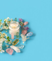 gemstones minerals, candle and flowers on blue background. Crystal ritual, Esoteric spiritual practice, relax time. Wiccan Witchcraft. copy space