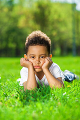  Little boy lies on green grass in a summer park
