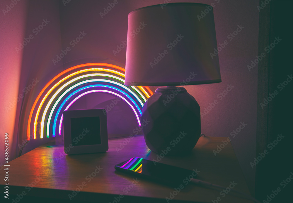 Wall mural glowing led neon rainbow on the side table in the evening