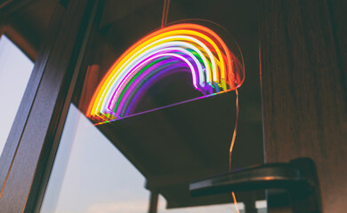 The led neon rainbow hanging on the door entrance in the cafe