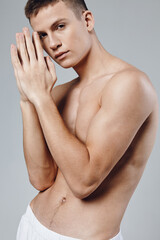 sporty man with pumped up muscles of his hands connected his fingers near the face on a gray background