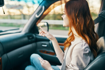 Naklejka premium happy woman traveling companion in the front seat of a car gesturing with her hands back view