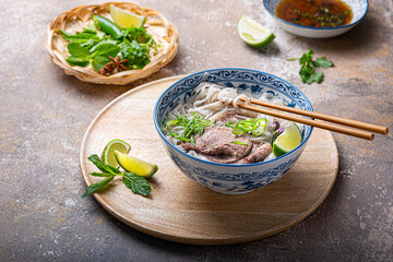 Pho bo with beef tonque, herbs, spicy sauce and lime - 438573649