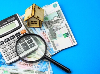 Miniature toy house, Russian rubles, magnifying glass, calculator on a colored background. Real estate object. Concept of buying an apartment, house. Rental of property.