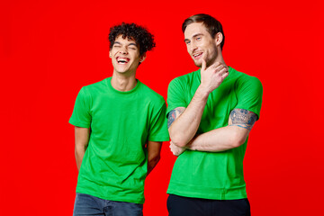 Fototapeta premium joyful friends in green t-shirts are standing next to red background