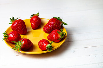 Ripe strawberries in a yellow plate