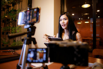 Young asian woman vlogger recording video content for online channel.female looking at camera and talking on video shooting.content creator maker or social influencer  concept
