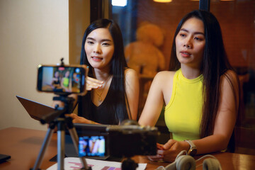 two asian women vlogger recording video content for online channel together.female looking at camera and talking on video shooting.content creator maker or social influencer  concept