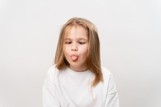 funny girl shows tongue and grimaces on white background
