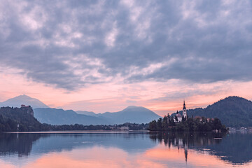 Fototapeta na wymiar Lake Bled in Slovenia viewed from the ground showing the pilgrimage church at sunrise in beautiful orange colors