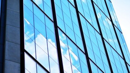 Blue sky and clouds reflected in windows of modern office building. Modern glass facade. 