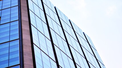 Blue sky and clouds reflected in windows of modern office building. Modern glass facade. 