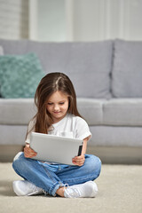 Little kid girl looking at tablet at home