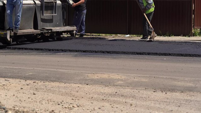 Road repair. Work details, workers pour resin road surface to cover the asphalt. Men in specialized clothing repair asphalt in the city. Preparation of asphalt pavement for laying new asphalt.