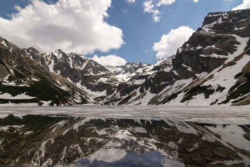  Mountain Lake of Czarny Staw Gasienicowy covered with snow and surrounding peaks of Tatra...