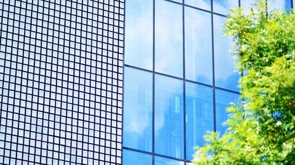 Blue sky and clouds reflected in windows of modern office building. Modern glass facade. 