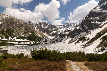 Fototapeta premium Mountain Lake of Czarny Staw Gasienicowy covered with snow and surrounding peaks of Tatra Mountains in Zakopane, Poland. High quality photo