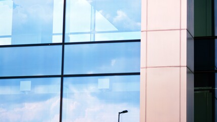 Blue sky and clouds reflected in windows of modern office building. Modern glass facade. 