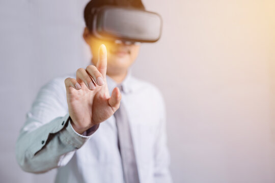 A male Thai teacher wearing virtual reality glasses with a fun and exciting gesture touch a model on a white background with his hand.