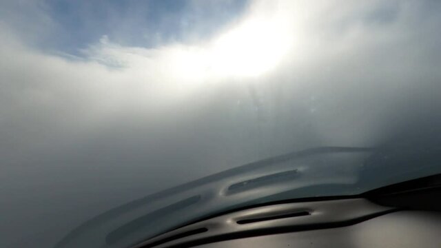 Plane flies through the clouds. Cocpit view. Blue sky and sun. 