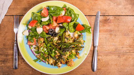 Scrambled eggs with asparagus and italian vegetable salad with mozzarella on a plate on a rustic background