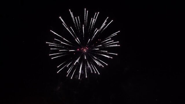 Glowing fireworks show. Fireworks with particles and sparks in the black night sky. Real Shot of fireworks background. Shining fireworks with bokeh. New year's eve firework celebration.