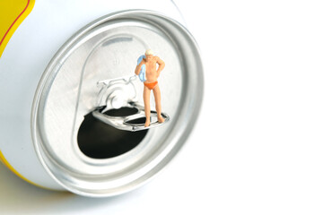 Obraz premium Miniature people toy figure photography. Creative summer vacation concept. A men standing above soft drink canned getting ready to swim.