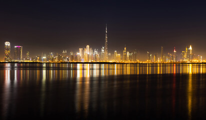 Fototapeta na wymiar Night view of Dubai city skyline with reflections on the water.