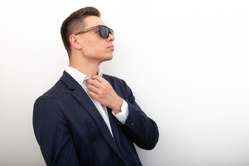 Business man in a jacket and white shirt straightens his shirt on a white background