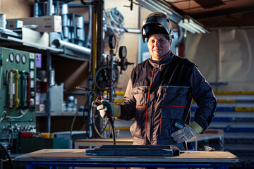 Fototapeta na wymiar Portrait of a smiling welder posing in the factory