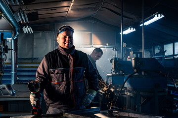 Fototapeta na wymiar Portrait of the grinding handyman posing in the workshop