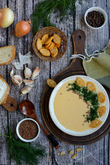 Vertical composition. Creamy potato soup with cheese, croutons and herbs on a wooden background. View from above