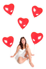 Portrait of a laughing young woman with many red heart balloons, isolated in front of white studio background