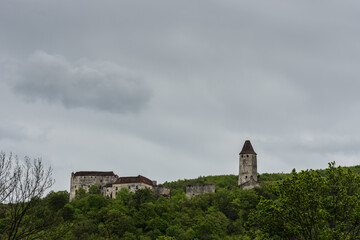Fototapeta na wymiar old castle in green hills with many trees and rain clouds